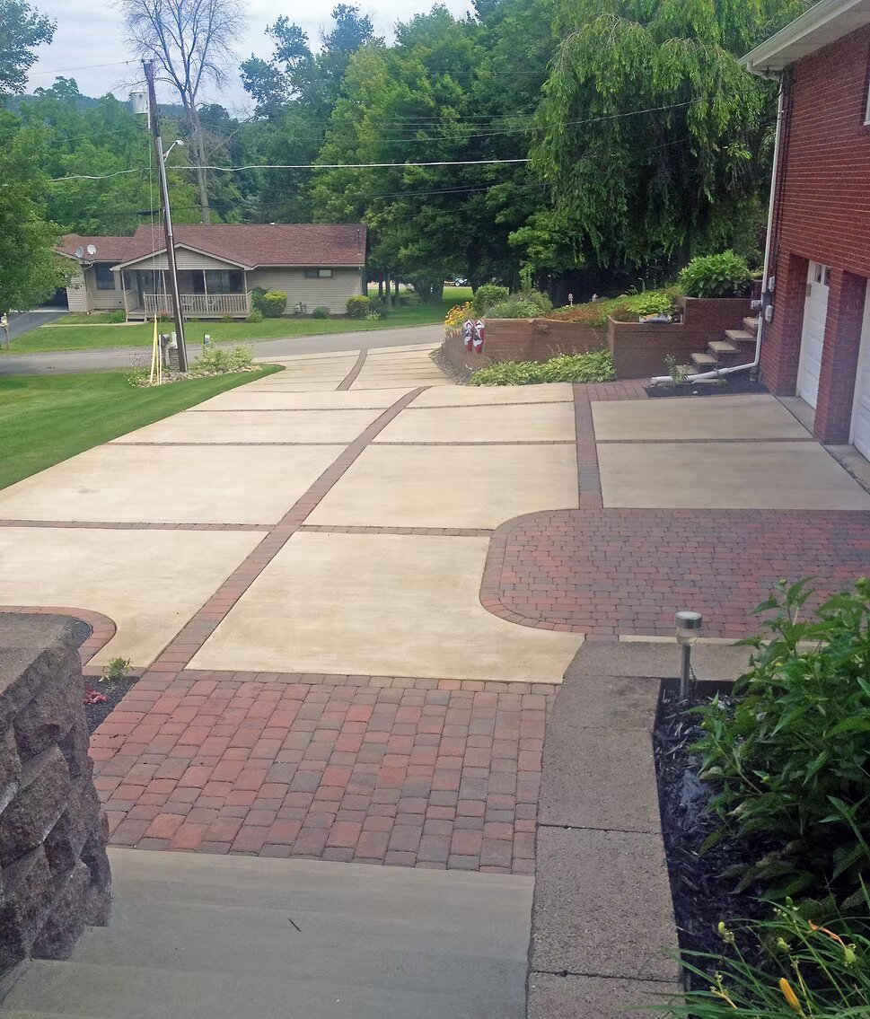 Concrete driveway with brick paver accent bands and circular turnaround at a brick home