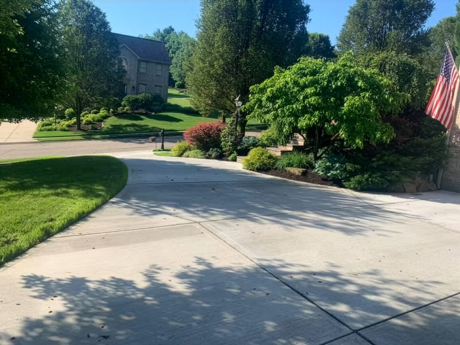 Large curved concrete driveway with crisp edges and landscaping at a residential home