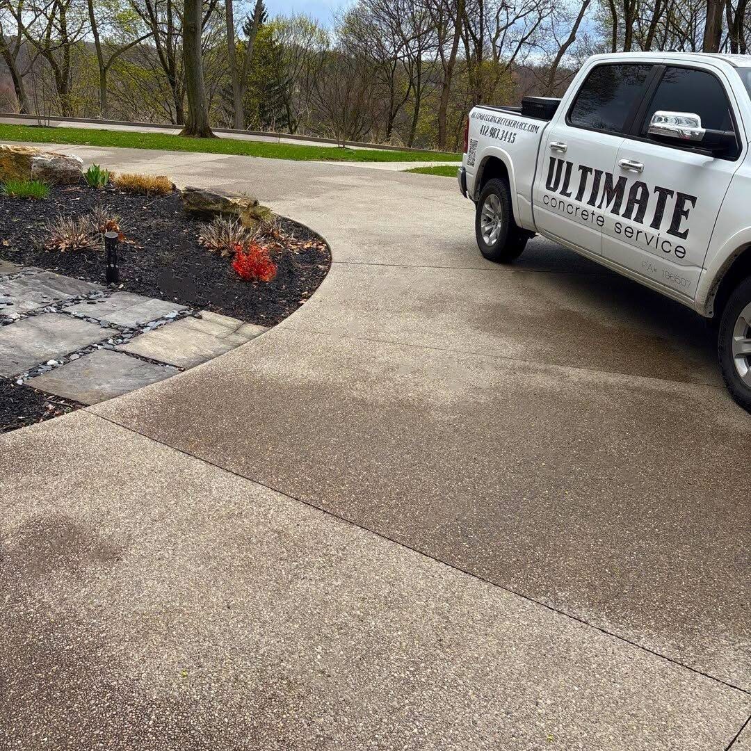 Exposed aggregate driveway with curved island landscape bed and Ultimate Concrete Service truck