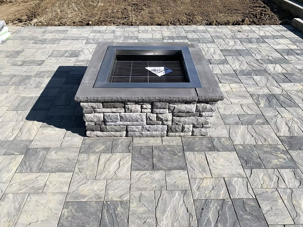 Built-in concrete fire pit with block surround on a stamped paver patio