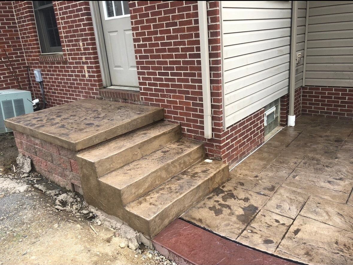 Concrete steps and landing with color accent at a brick home