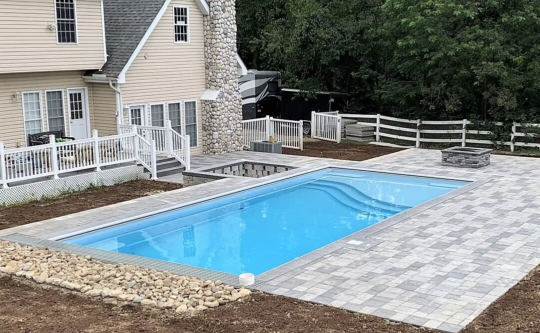 Stamped paver pool deck with fire pit and raised patio surrounding a rectangular in-ground pool