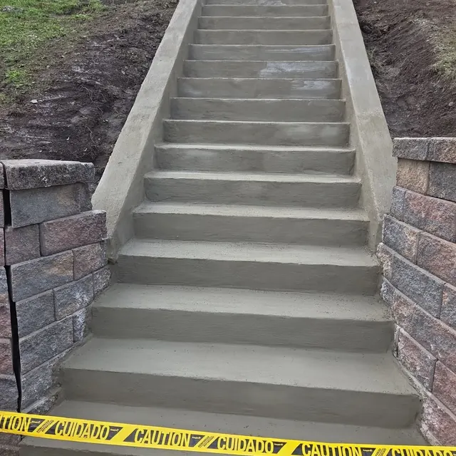 New concrete stairway with side walls and block retaining walls on a residential slope