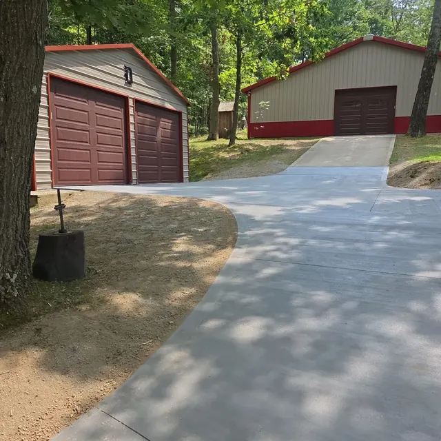 Curved broom-finished concrete driveway leading to two detached garages
