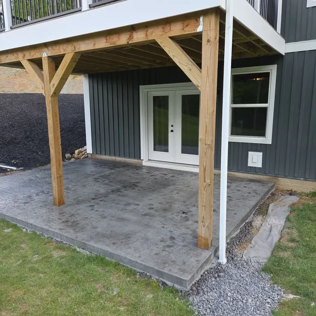 New concrete patio beneath a raised deck at a modern home