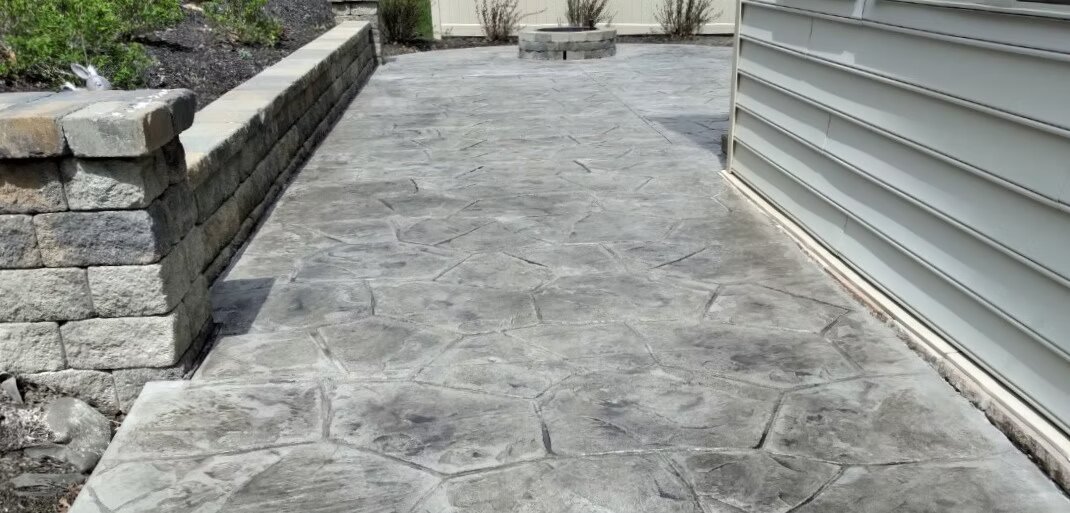 Ashlar flagstone stamped concrete patio with block retaining wall and fire pit